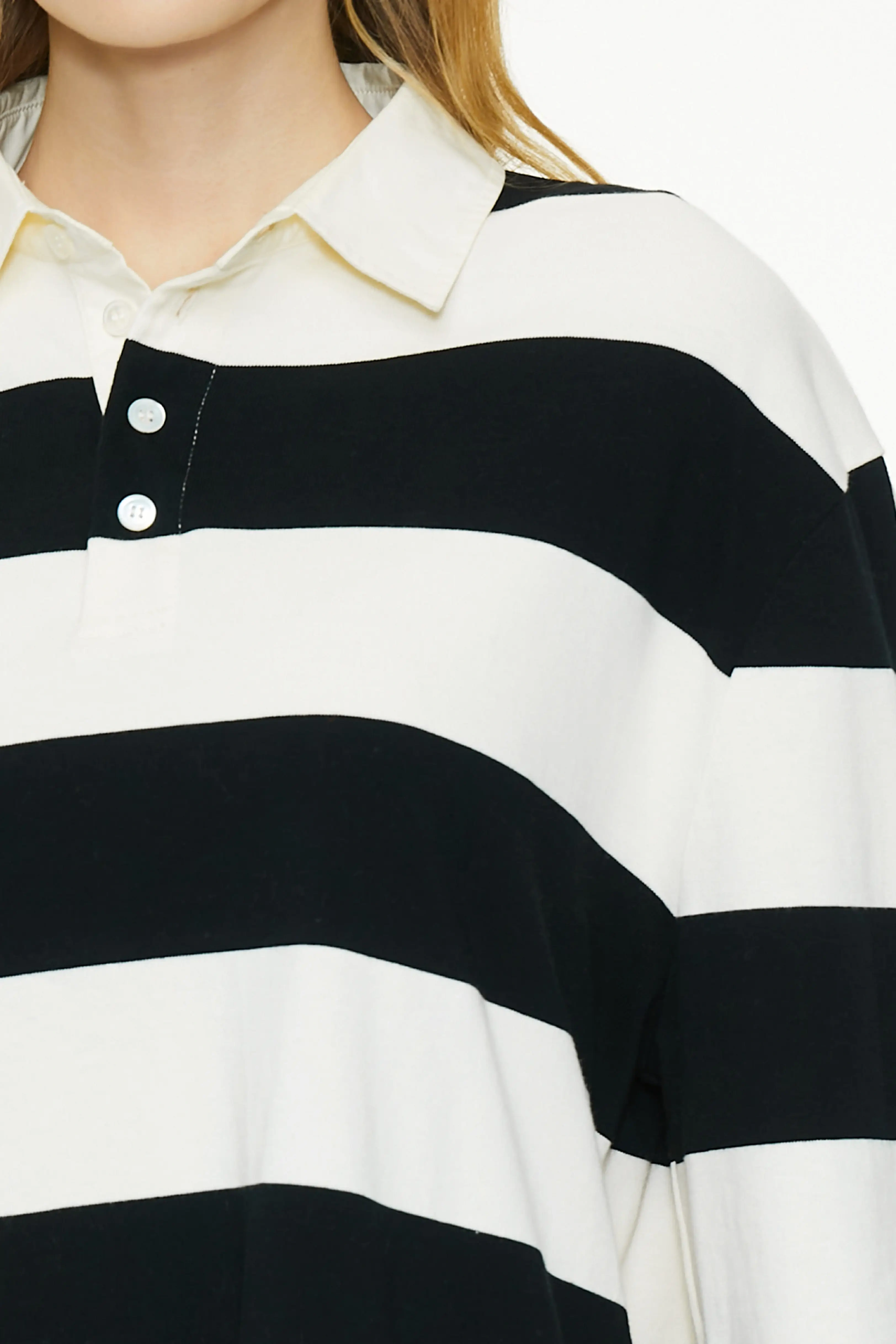 Close-up shot highlighting the contrast white polo collar and two-button placket on the black and white striped rugby shirt.