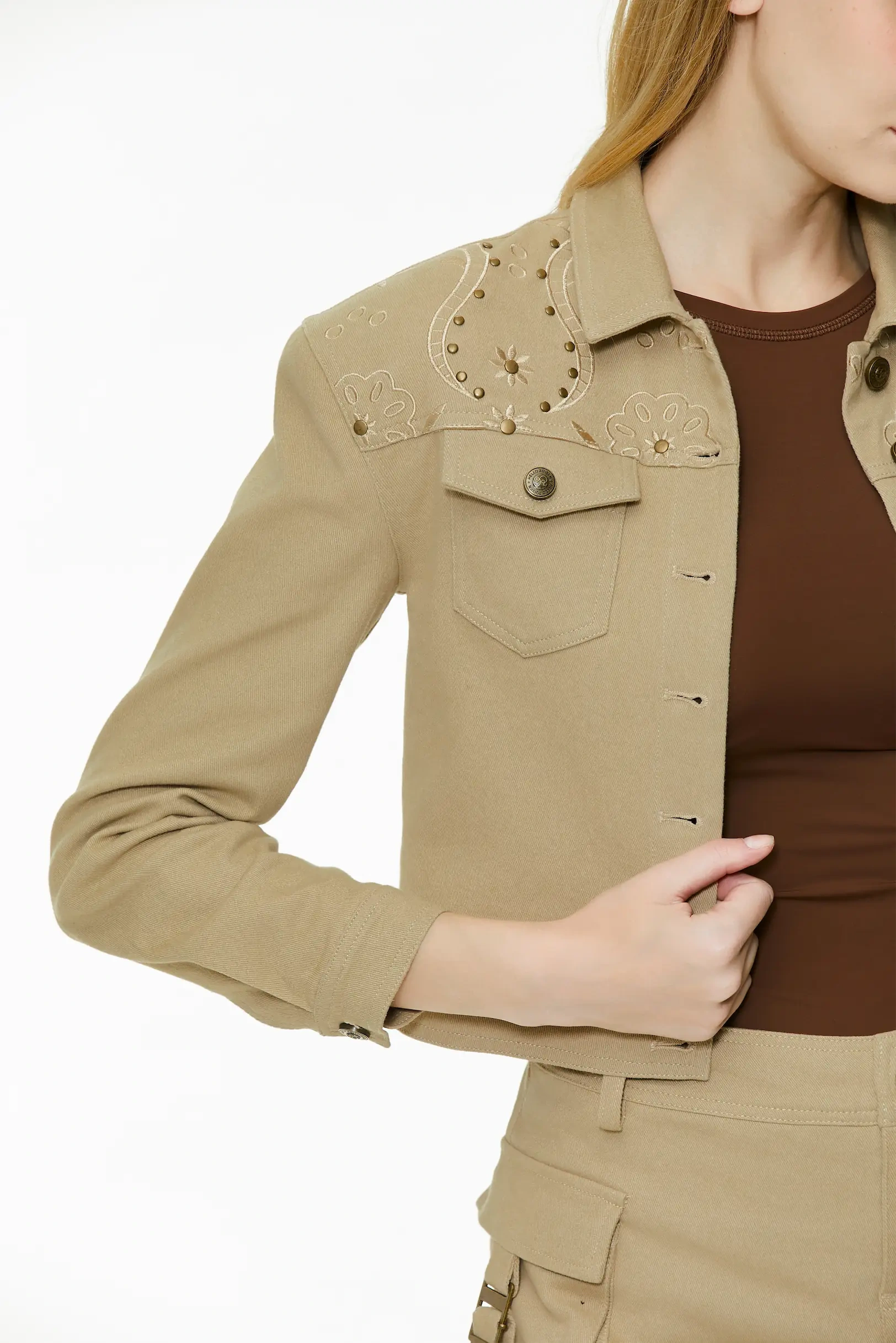 Side close-up view highlighting the sleeve structure, shoulder studs, and side profile of the khaki cropped jacket.