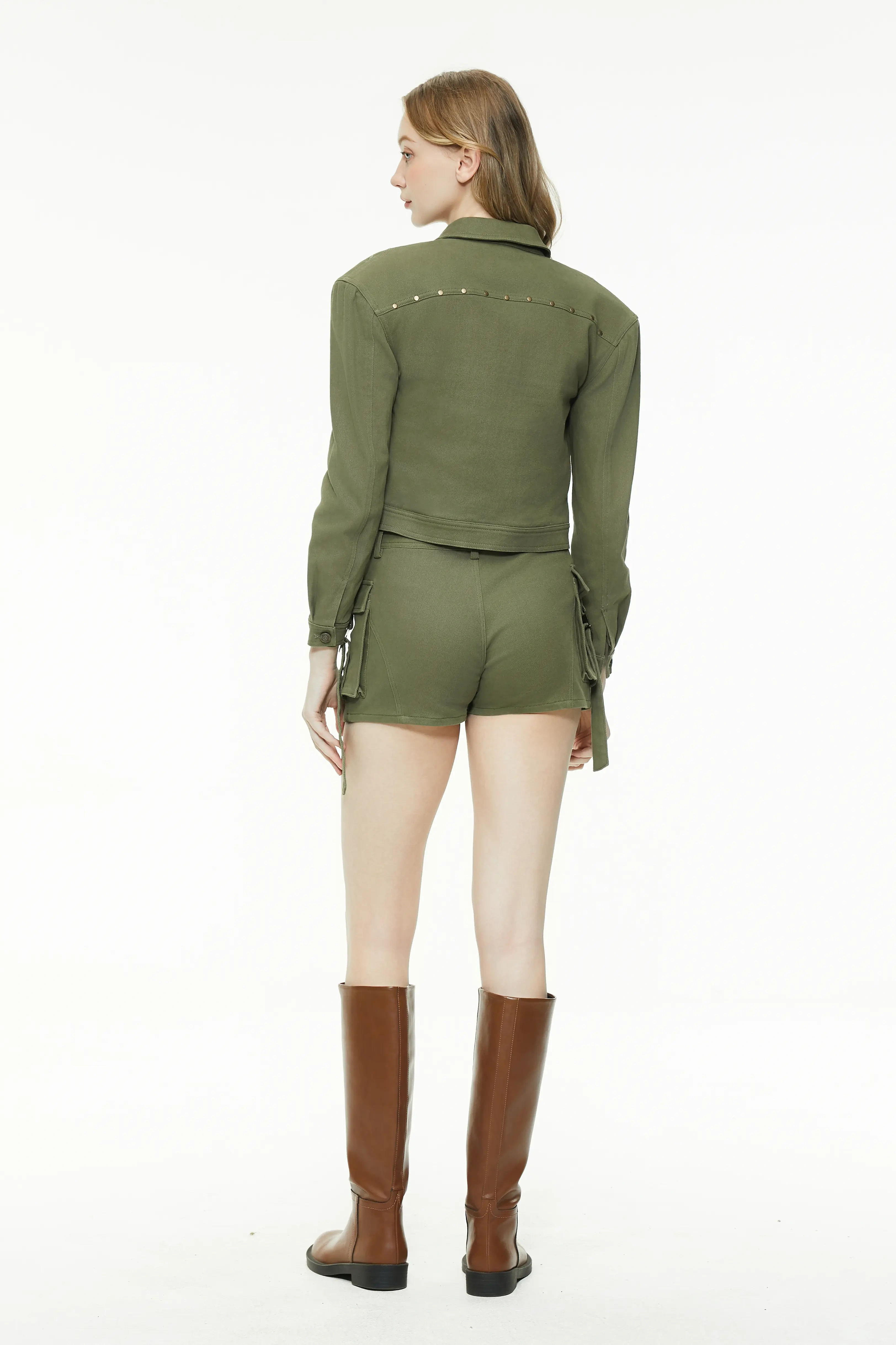 Full body back view of a model wearing an olive green long-sleeve cropped jacket showing the fitted back seam silhouette and matching skirt.