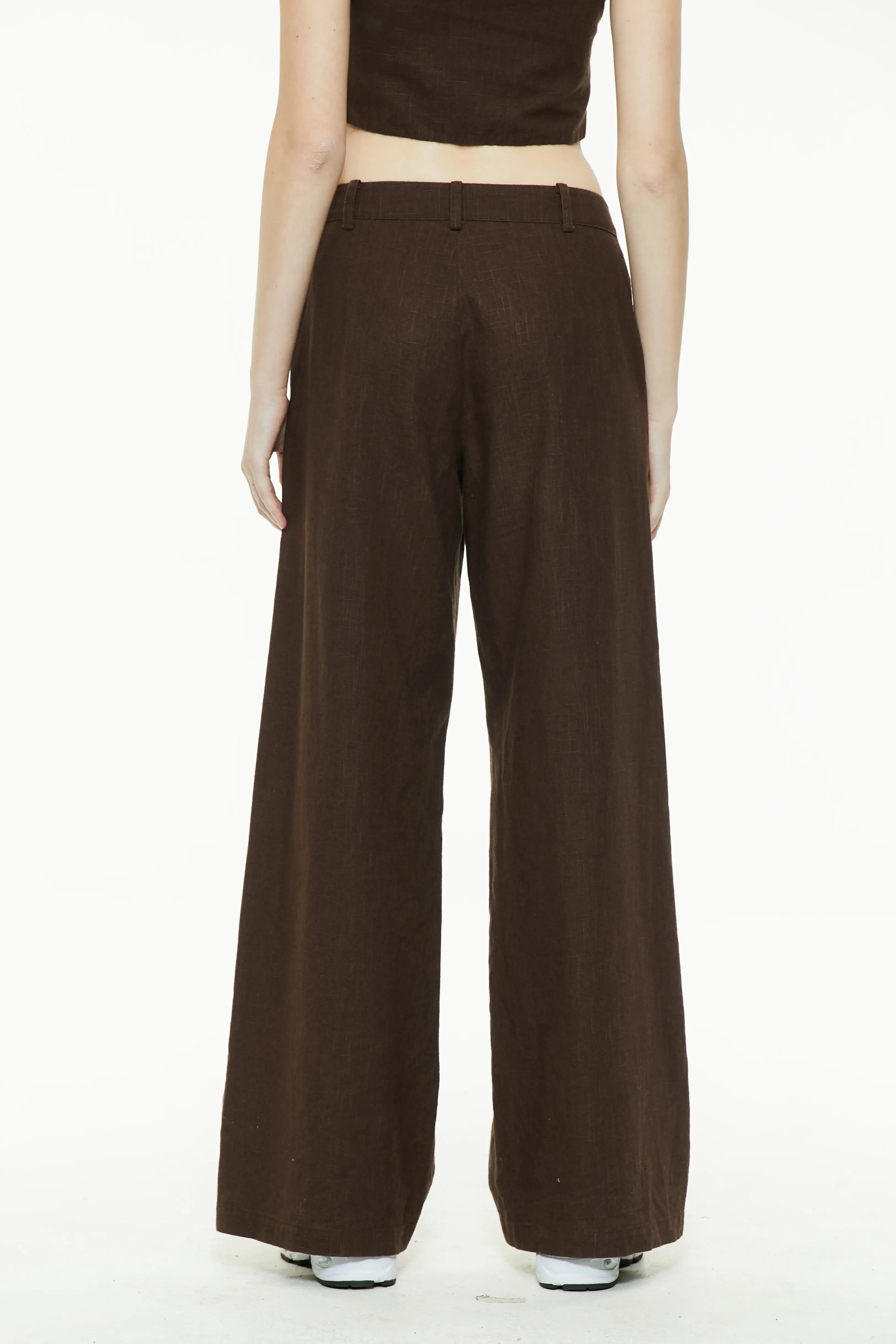 Back view of brown linen wide-leg trousers showing a clean waistband and relaxed fit legs.