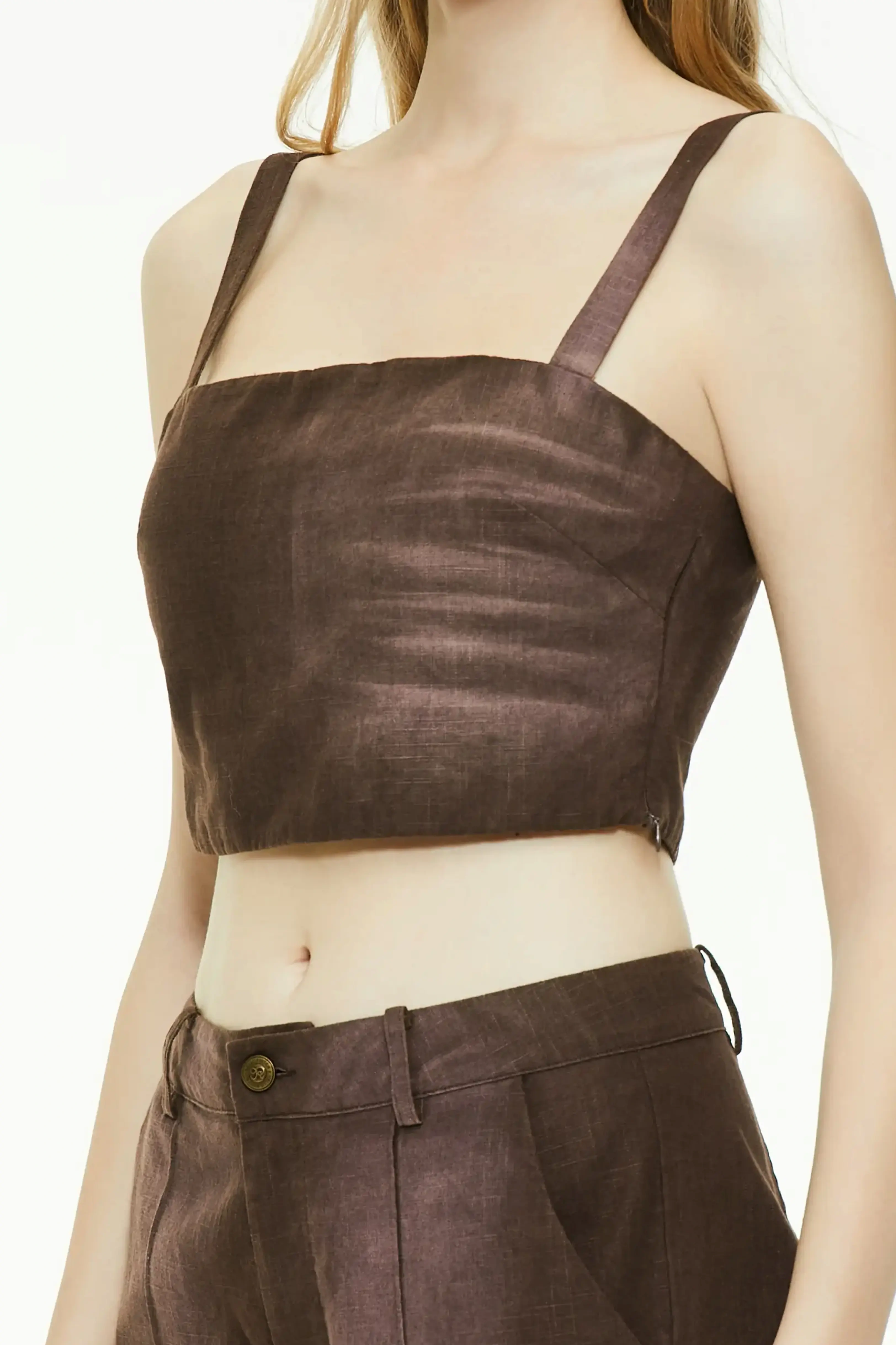 Close-up front view of a brown square-neck cropped top showing the smooth texture, thick shoulder straps, and side zipper structure.