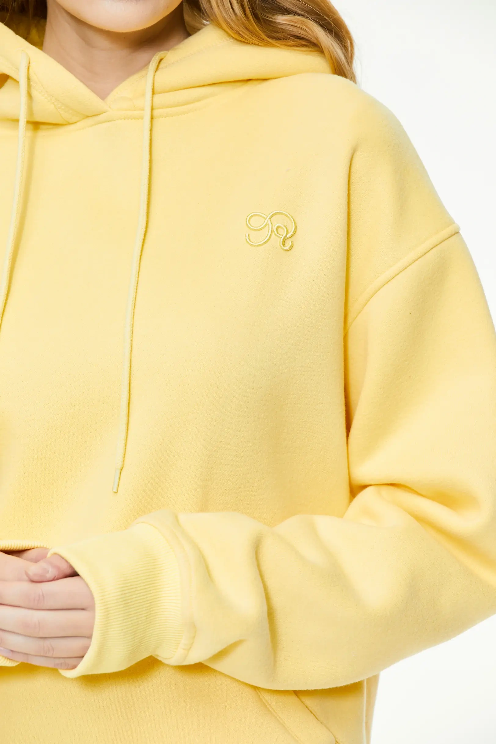 Yellow hoodie highlighting the chest embroidery and soft fabric texture