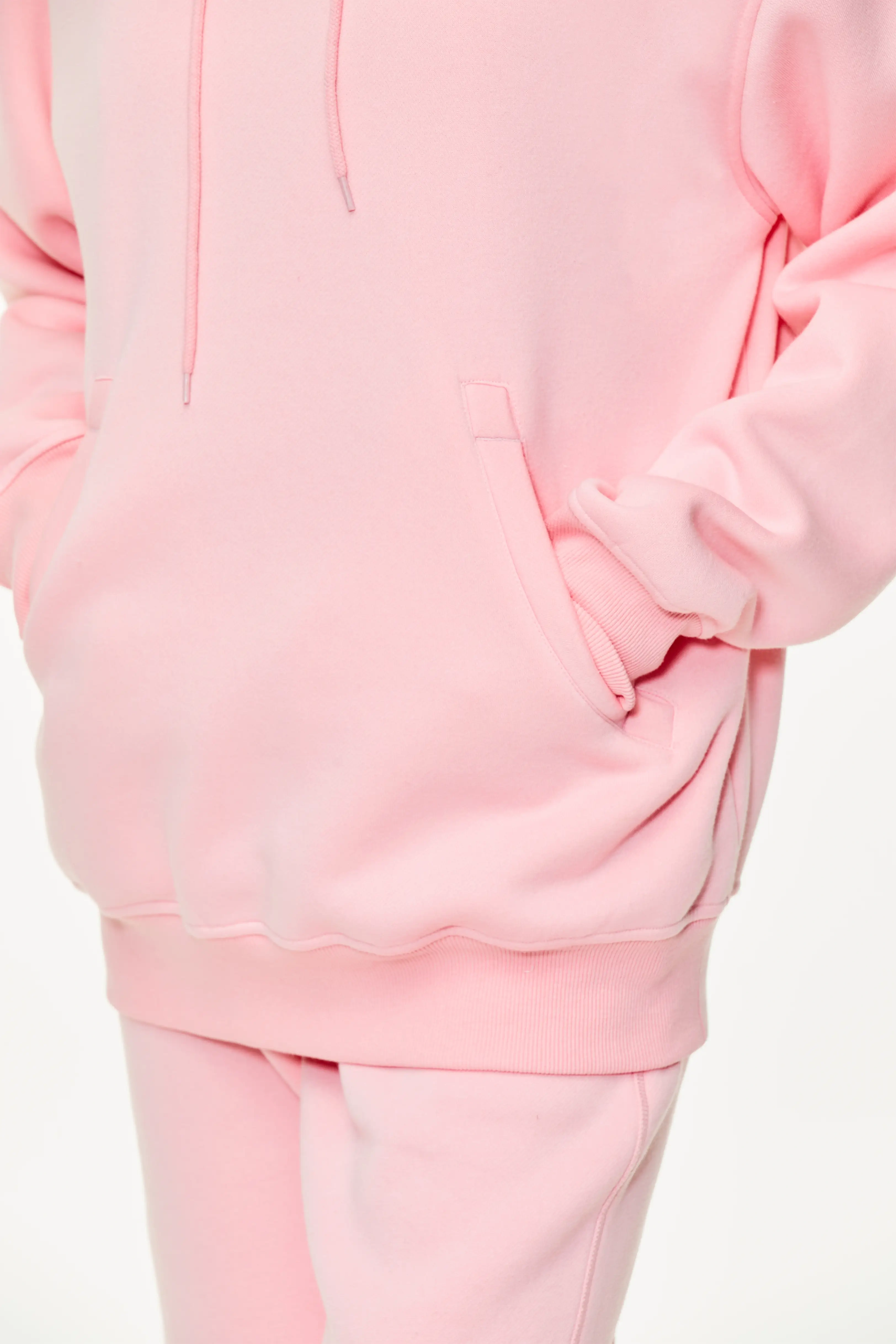 Pink drop shoulder hoodie highlighting the front kangaroo pocket and fabric texture