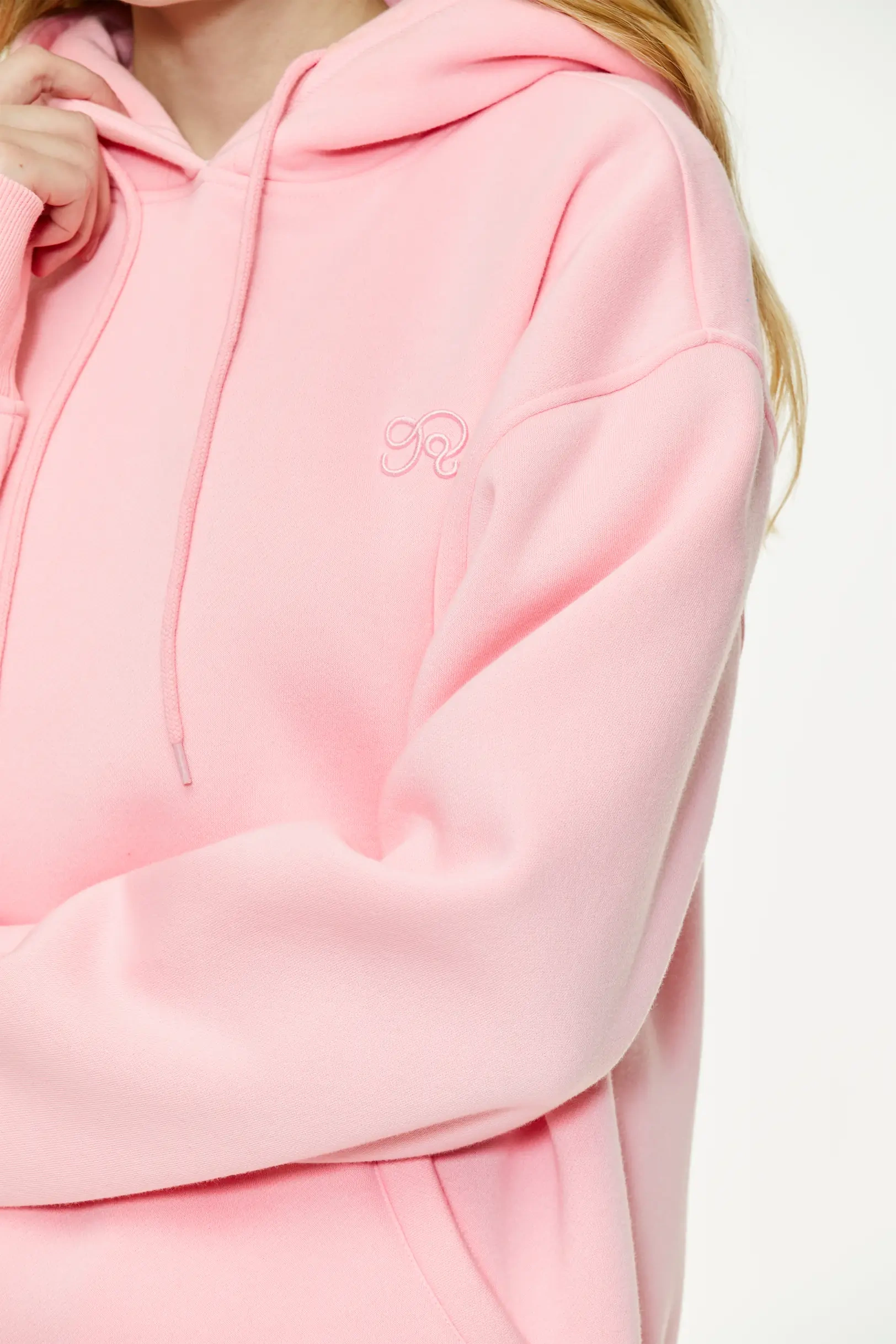 Pink hoodie with subtle embroidered logo detail and textured cotton blend