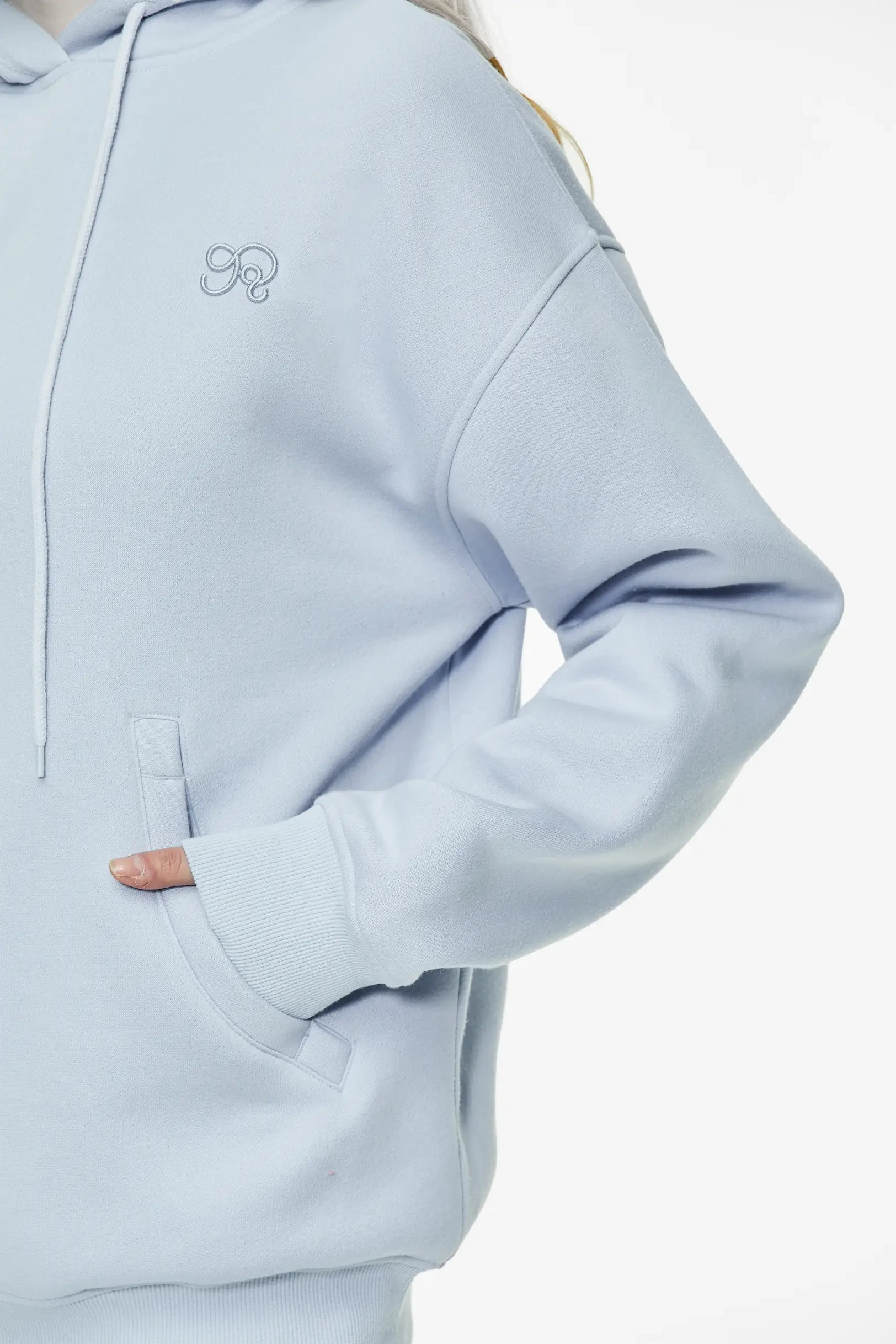 Light blue drop shoulder hoodie featuring sleeve and subtle embroidered design
