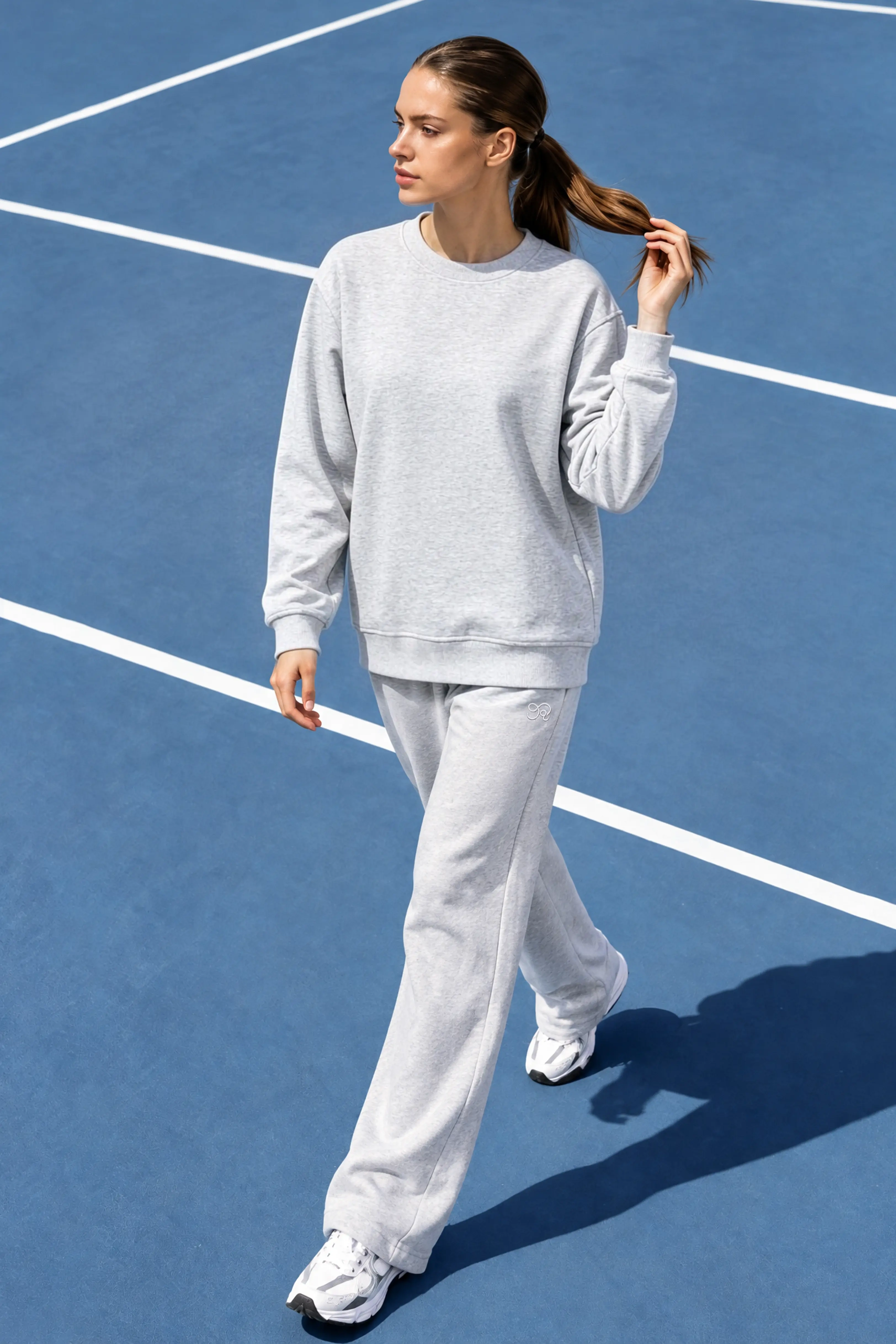 Gray wide leg sweatpants with matching crewneck sweatshirt on a tennis court