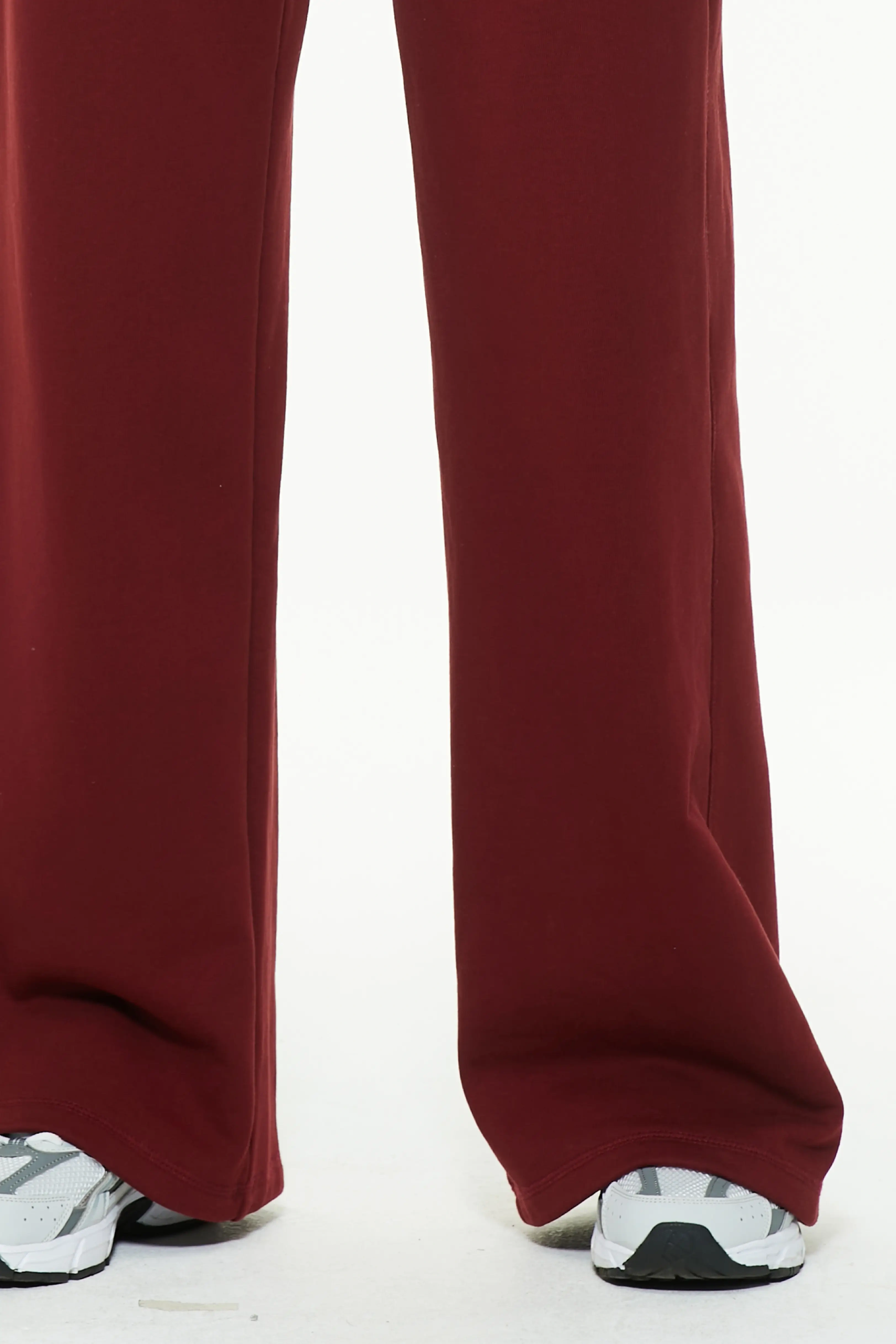 Close-up of burgundy wide leg sweatpants showing loose leg opening and sneakers