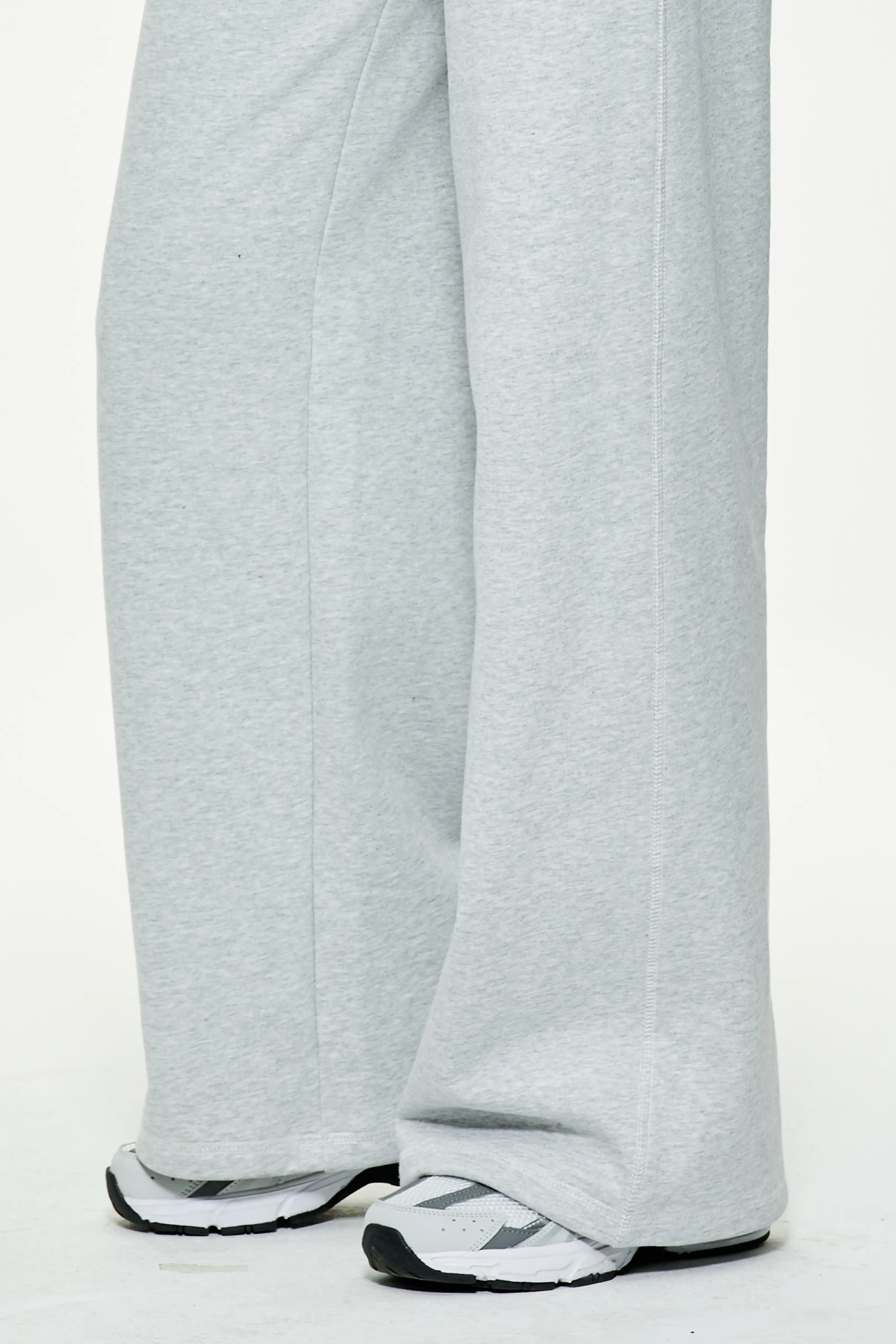 Close-up view of heather gray wide leg sweatpants hem and athletic sneakers