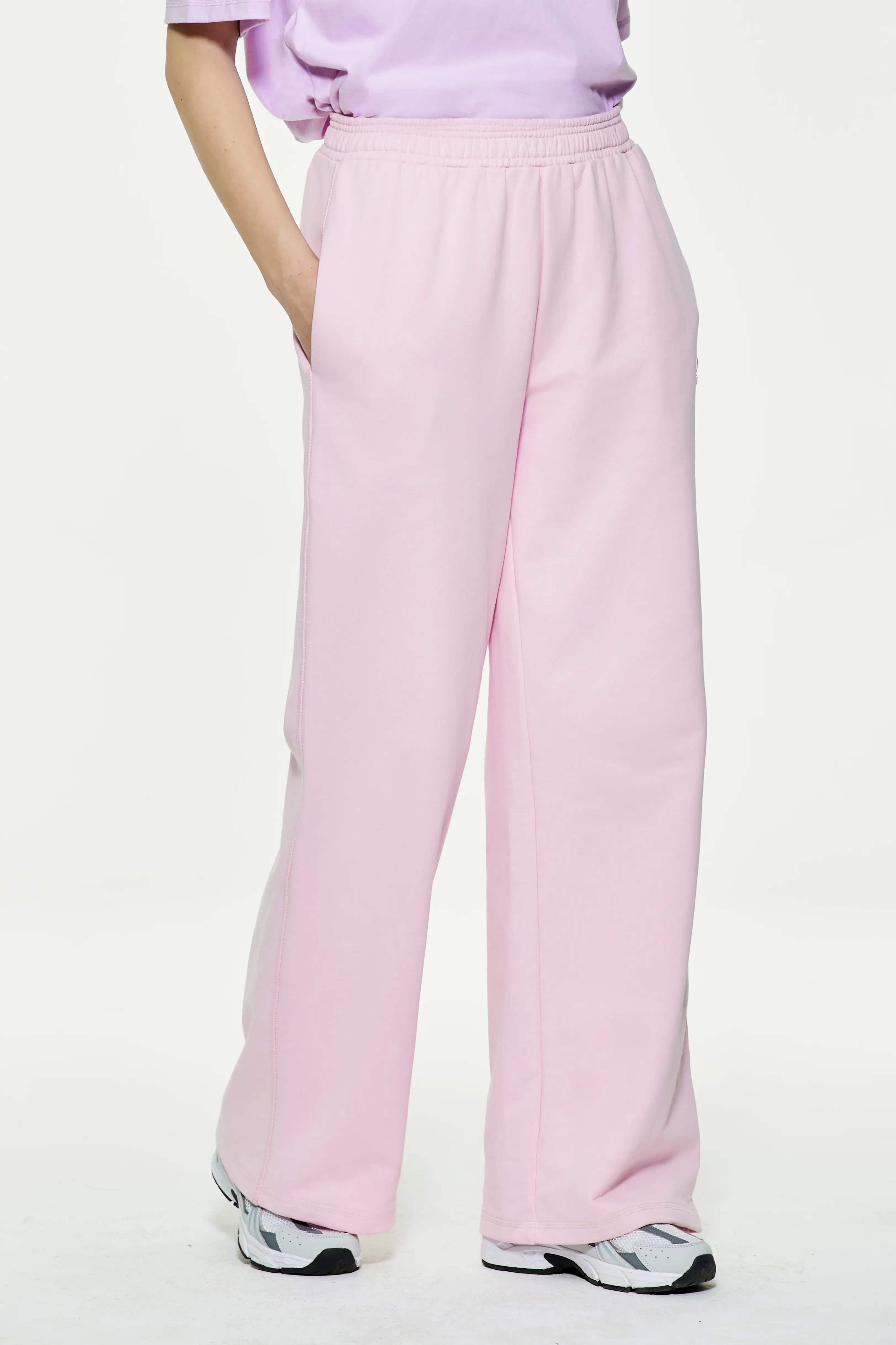 Light pink wide leg sweatpants featuring side hand pockets and loose drape
