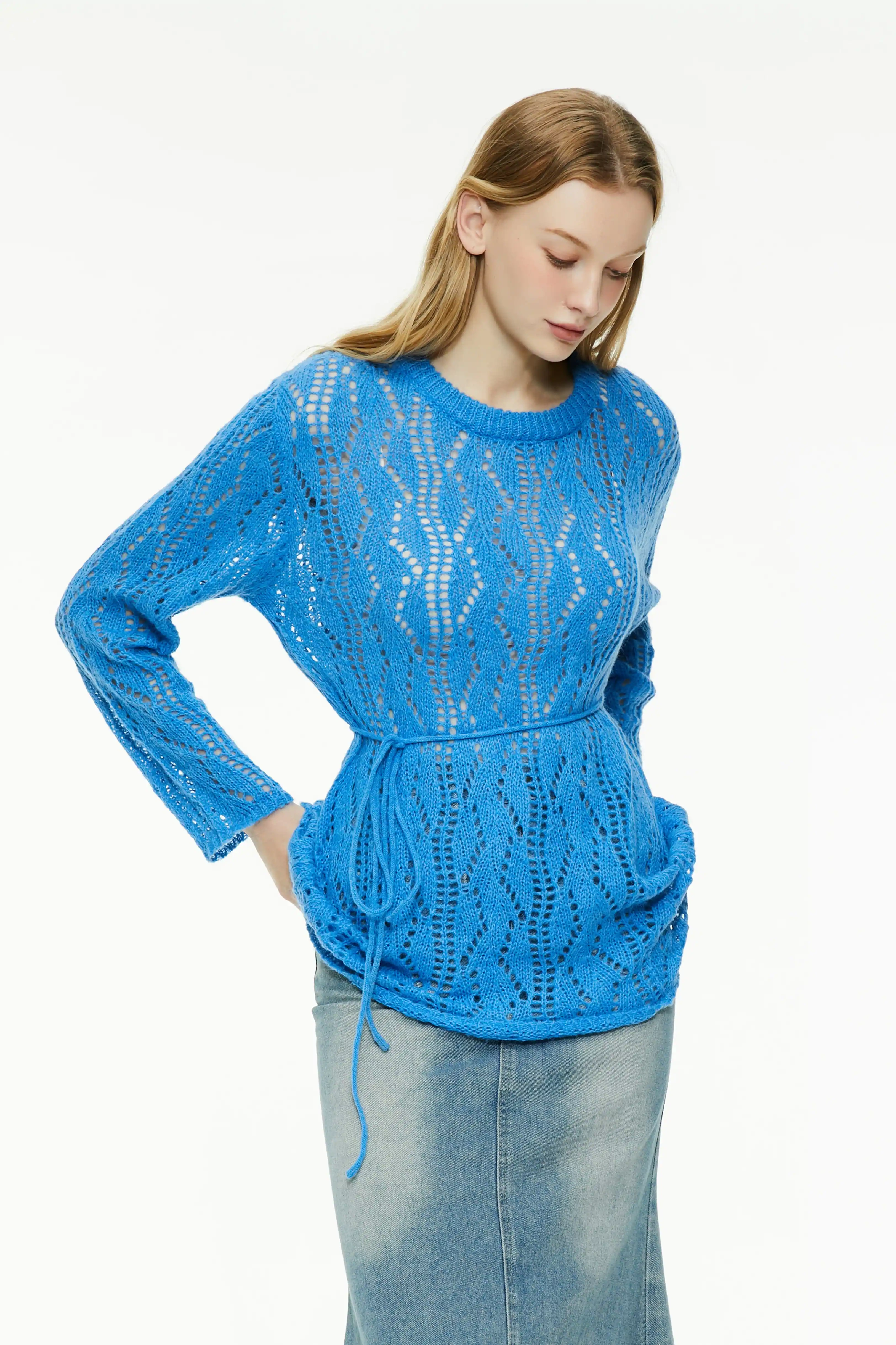 Blue sheer knit sweater with long sleeves and an adjustable waist drawstring paired with a denim skirt