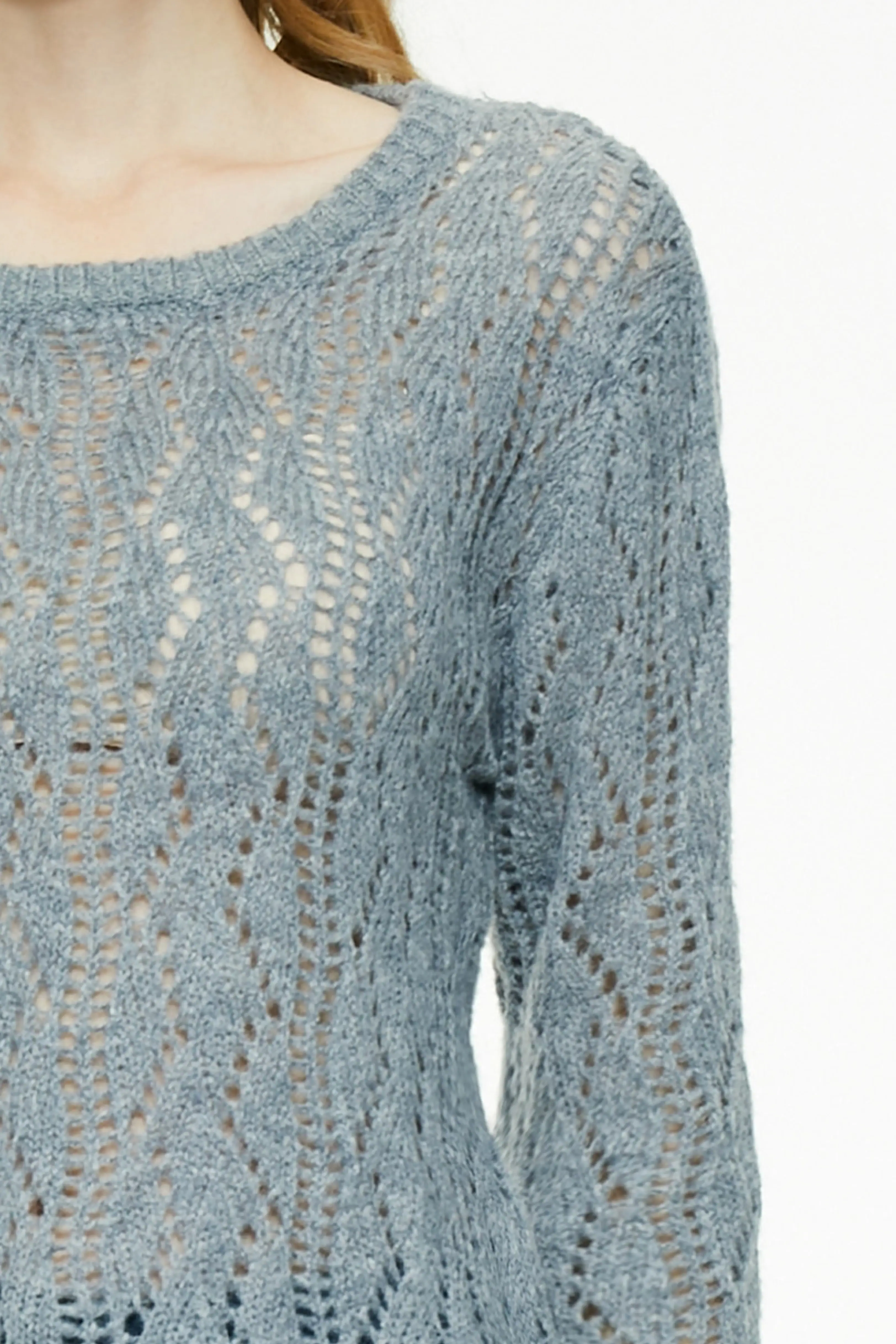 Extreme close-up of the textured open-work knit pattern on a gray sweater
