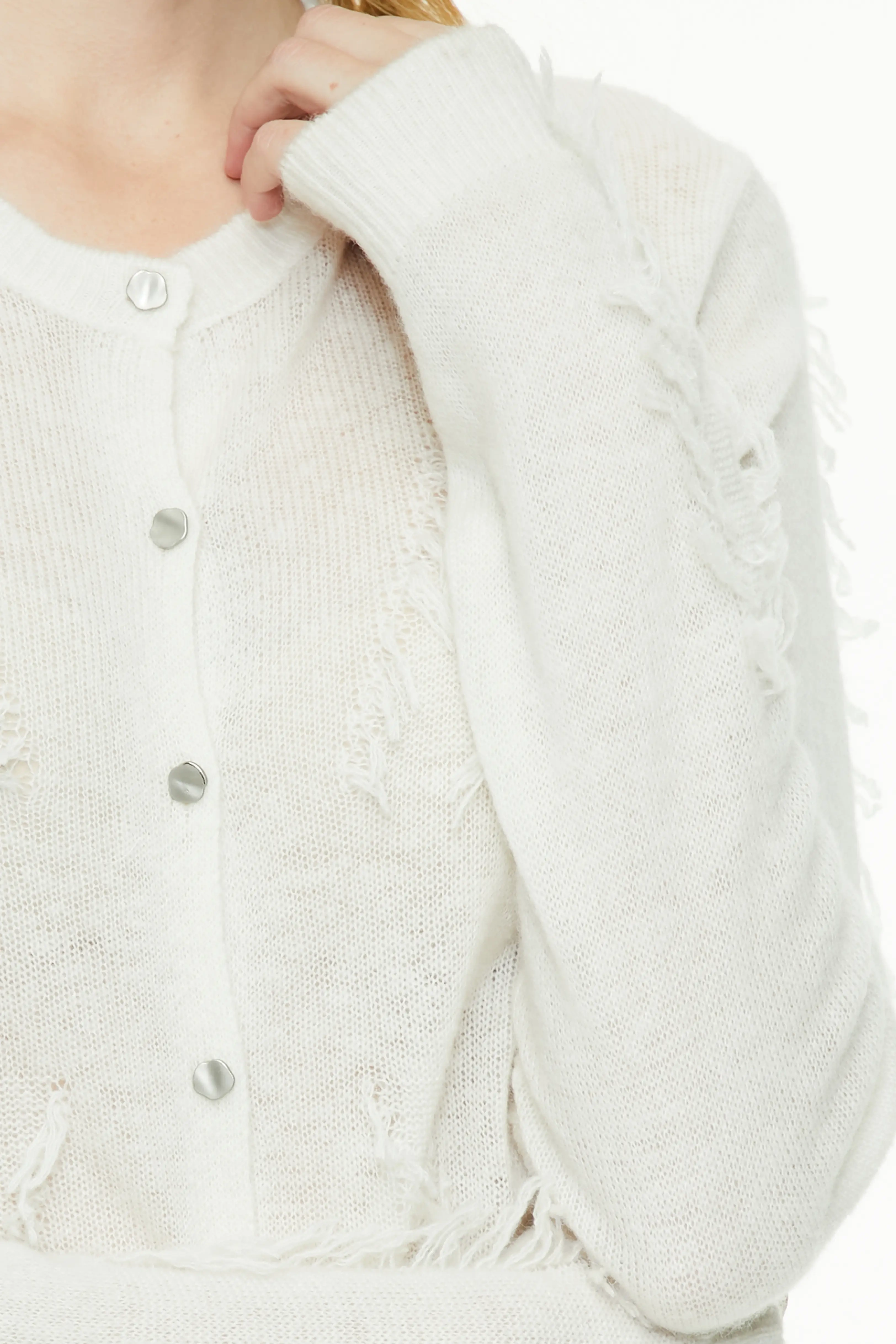White cardigan highlighting the textured knit pattern, round neckline, and pearl-style buttons