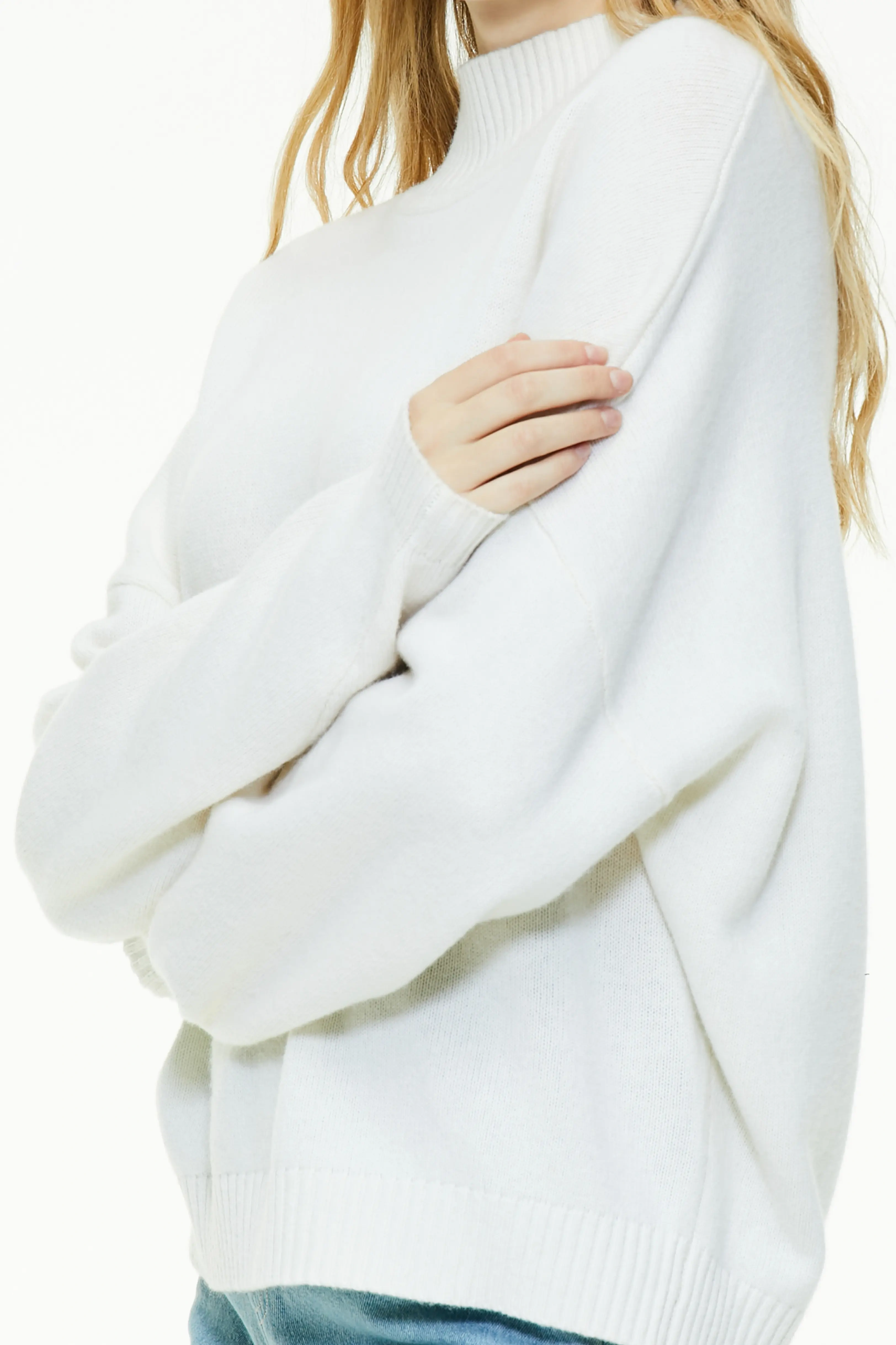 Close-up of white turtleneck sweater highlighting soft ribbed knit texture and wide sleeves