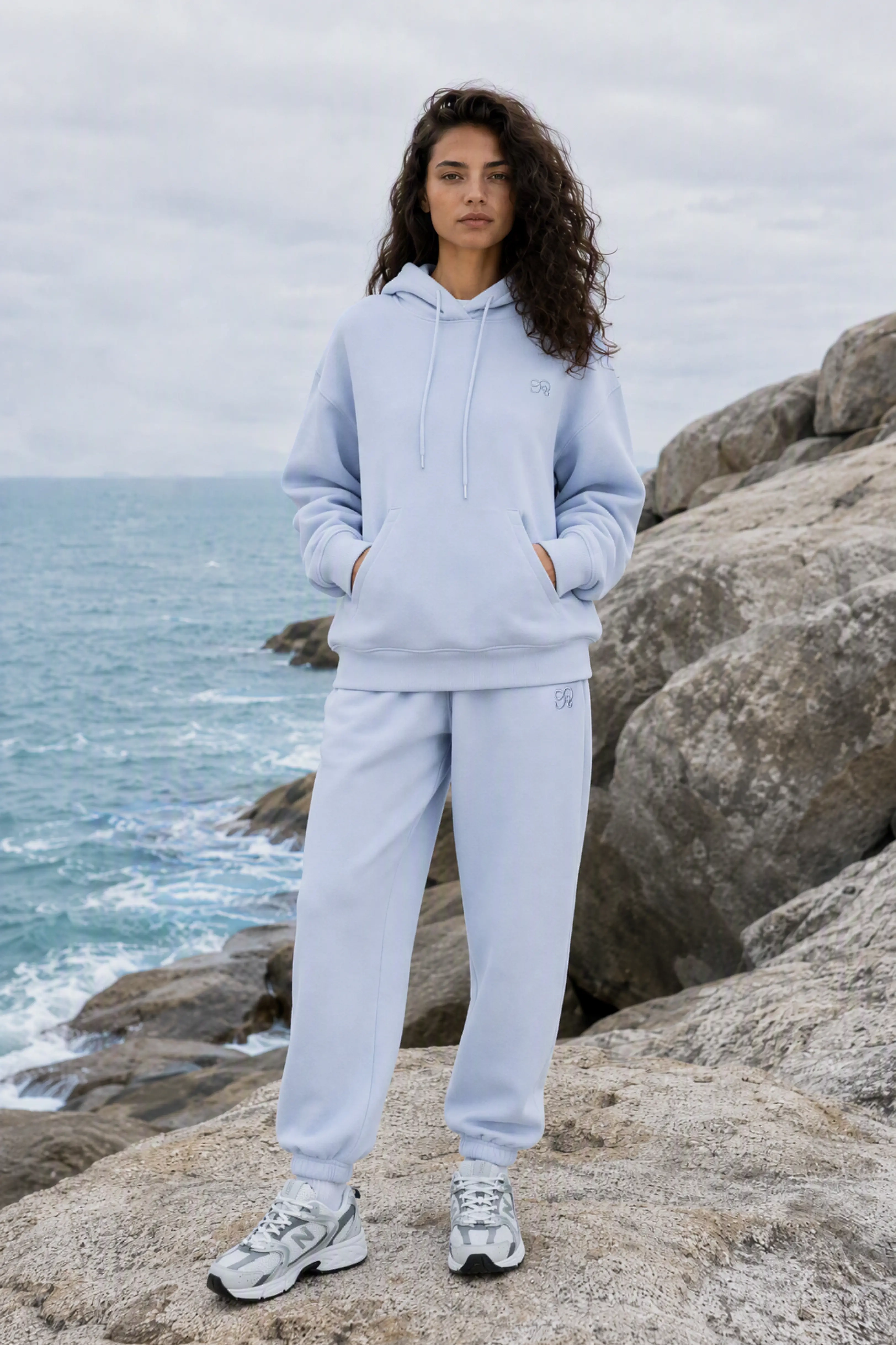 Close-up of blue relaxed fit sweatpants highlighting side pocket and embroidered logo