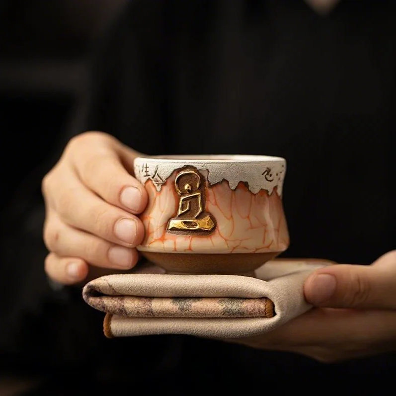 Eartivo Abstract Ascent cup, aged mineral clay, ice-crackle graze with a golden buddha sculpture.