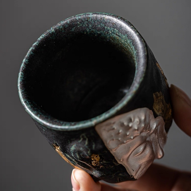Close-up view of Eartivo "The Duality Insight" vessel, showcasing the contrast between the rough-hewn Rock-Mineral side and the handcrafted gold-covered Buddha; designed to naturally develop a deep, rich "patina" over time through daily use.