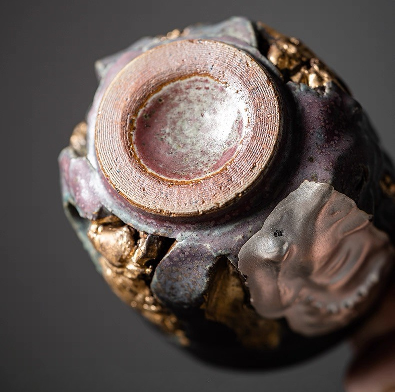 A bottom view of Eartivo "The Duality Insight" vessel, showcasing the contrast between the rough-hewn Rock-Mineral side and the handcrafted gold-covered Buddha; designed to naturally develop a deep, rich "patina" over time through daily use.