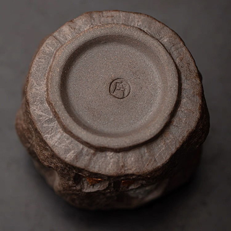 Close-up of the base of Eartivo "The Stone Sanctuary", showing the tactile grit of unrefined high-iron Dehua clay and the authentic maker's seal; a profound fragment of a lost Silk Road narrative, grounded on your tea table.