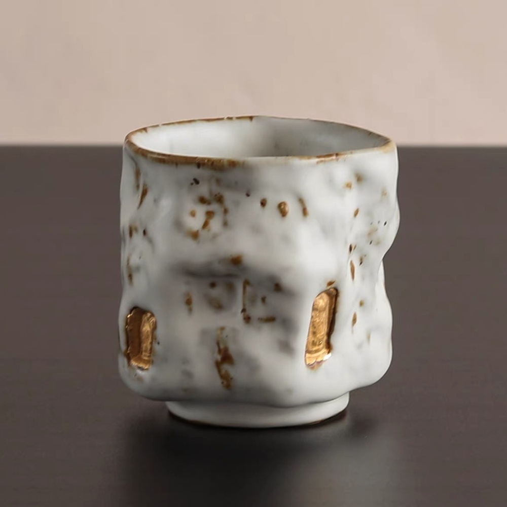Front view of The Snow-Buried Solitude Wabi-Sabi tea cup with a deeply buried, blurred golden Buddha icon under a heavy white clay glaze.