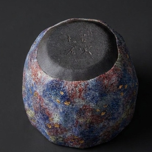 Macro close-up of the unglazed foot ring and precise circular form of the "Cosmic Bloom" rock-mineral tea cup against a dark background.