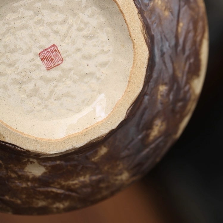 Detailed bottom view of the Dharma & Ash plate, featuring hand-carved clay trimming marks, distressed dark outer finish, and a distinct artisan red square seal mark.