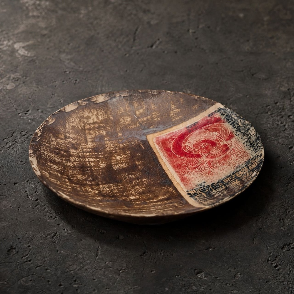 The Dharma & Ash artisan ceramic plate shows its subtle curved rim profile and rustic wabi-sabi aesthetic in warm ambient light.