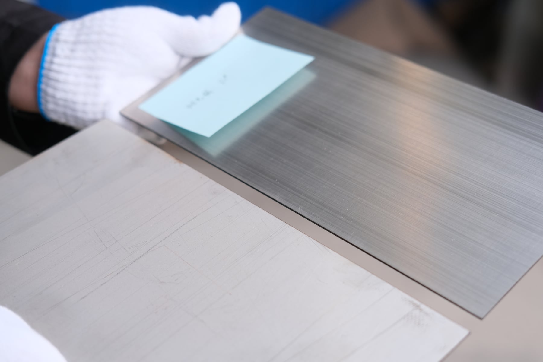 Stainless steel sheet samples showing directional brushed texture and visible surface marks