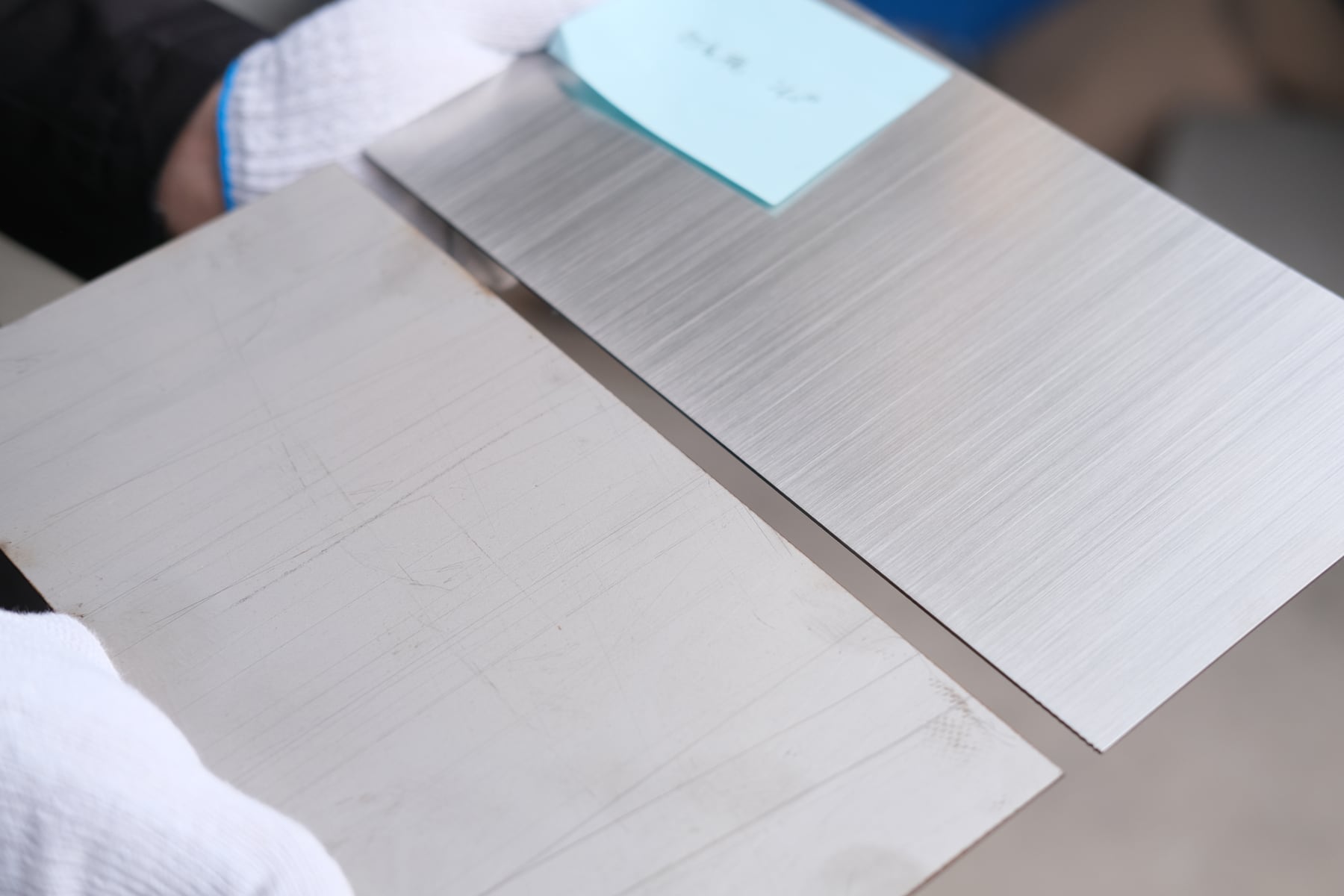 Additional view of stainless steel sheet samples with directional brushed surface texture