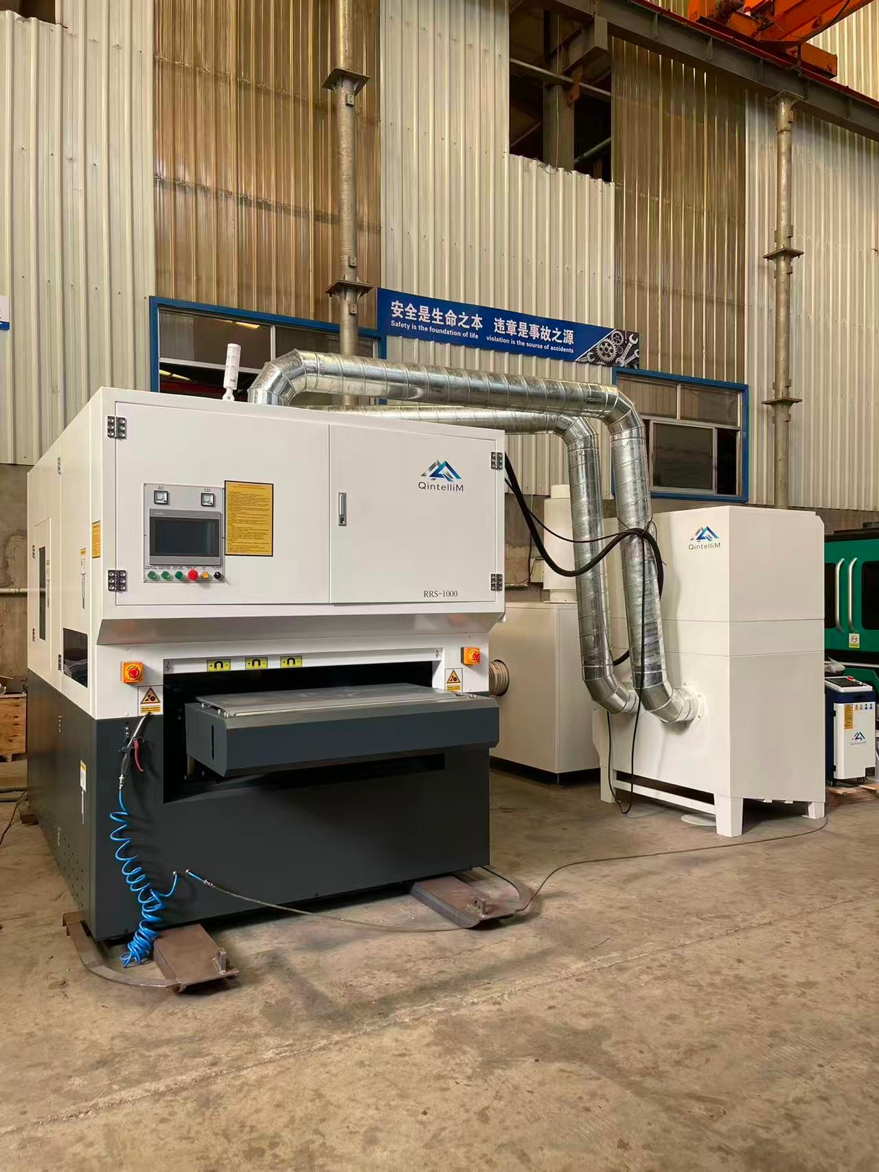 QintelliM RS-Series machine with connected extraction ducting and supporting equipment in the workshop.