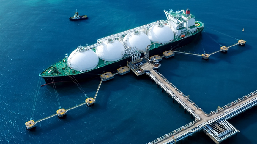 Aerial view of an LNG carrier ship docked at a marine terminal for cryogenic cargo loading and unloading operations.