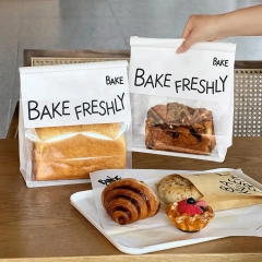 Printed bread bags with clear windows beside a pastry tray in a bakery cafe
