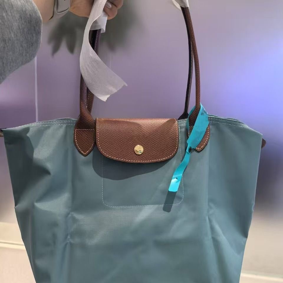 LONGCHAMP medium tote bag with gold hardware, snap buttons, and zipper closure.
