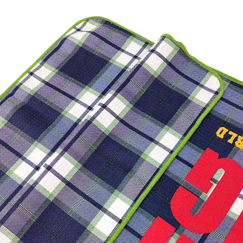 Branded golf towel with bold custom logo on plaid surface