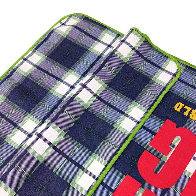 Branded golf towel with bold custom logo on plaid surface