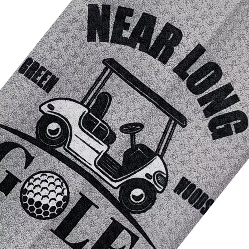 Custom logo golf towel with golf cart graphic on gray surface