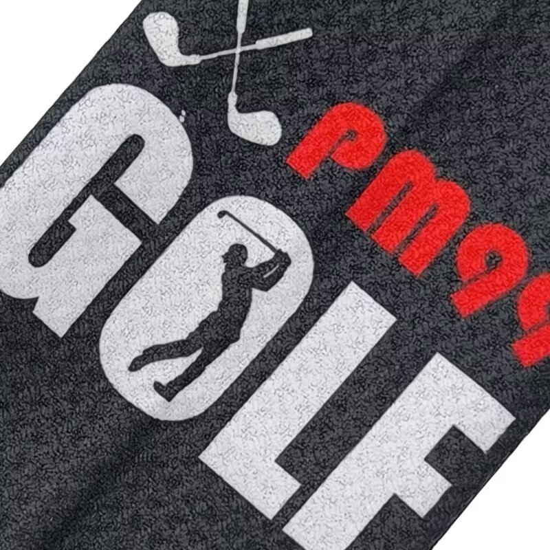 Custom logo golf towel with PM99 golf graphic on black surface