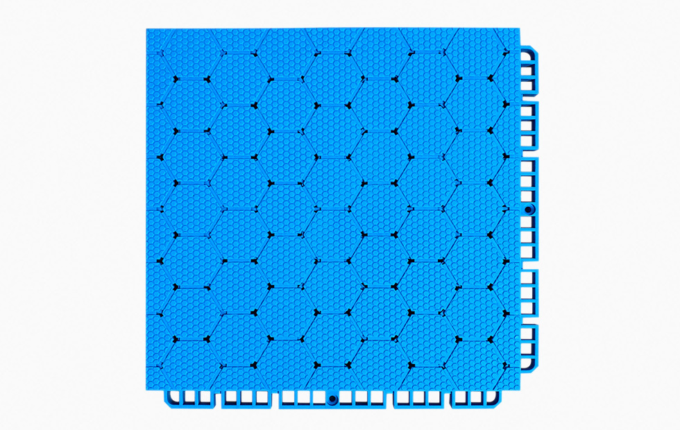 Underside view of a 250×250×16mm TPR sports tile showing the octagonal bottom support structure and two-way drainage channel geometry, which distributes vertical load across the substrate and facilitates rapid water runoff on installed outdoor sports surfaces.