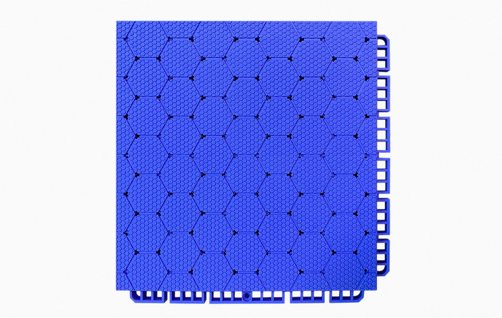Top-down view of a 250×250×16mm thermoplastic rubber sports flooring tile showing the thickened hexagonal surface pattern in grass green, designed to provide anti-slip traction and wet-surface grip on outdoor school sports courts and municipal fitness facilities.