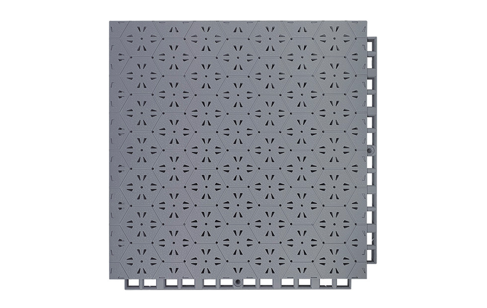 Installed 305×305×14mm thermoplastic rubber safety flooring tiles on an outdoor dual-use surface serving a sports field and kindergarten activity area, showing the patchwork thermal expansion joint design between adjacent tiles, uniform family hexagonal surface texture, and consistent tile alignment across the installed area.