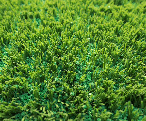 Close-up macro view of five-leaf type TPE eco-friendly artificial grass infill granules showing the five-lobe radial particle geometry designed to interlock within synthetic turf fiber piles for lateral migration resistance on football, rugby, and multi-sport synthetic grass surfaces.
