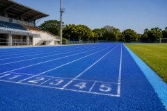 On the blue hybrid synthetic running track at the sports field.