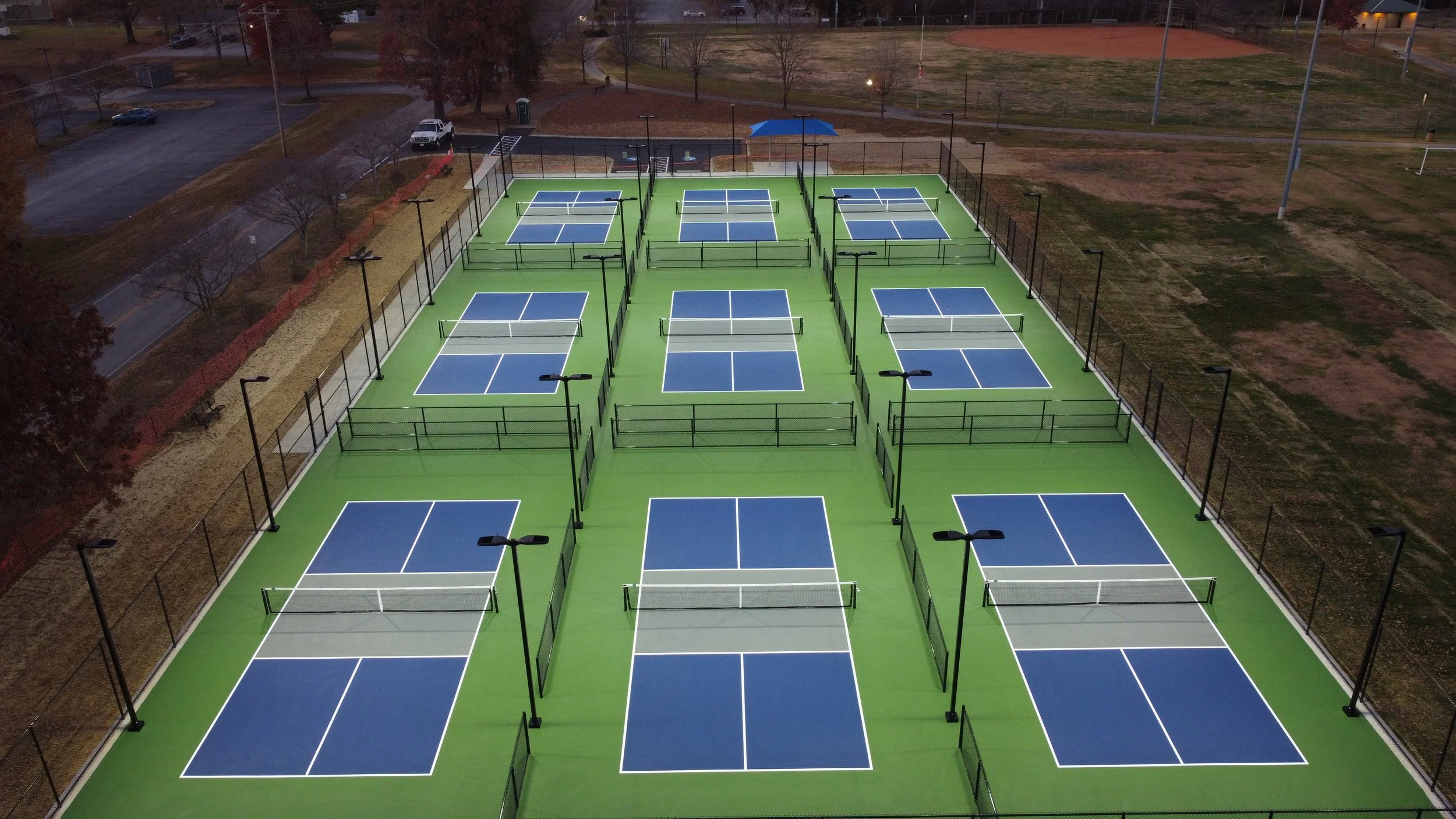 Four-pole full-cutoff LED lighting layout on a modular hardcourt pickleball system at night showing zero light spill.