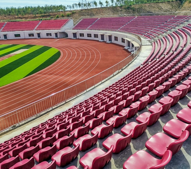 Side-by-side material comparison of Eco-M HDPE 5502 blow molded stadium seat versus polypropylene stadium seat, showing shell wall section, surface finish, color saturation, and structural profile differentiation