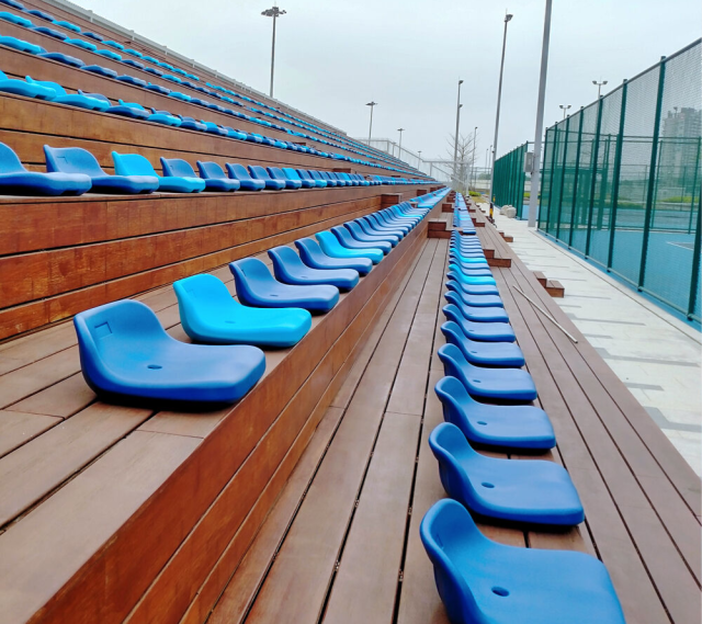 Outdoor stadium seating installation featuring HDPE 5502 blow molded seats deployed across a multi-row bleacher array, showing full structural context and seating capacity layout