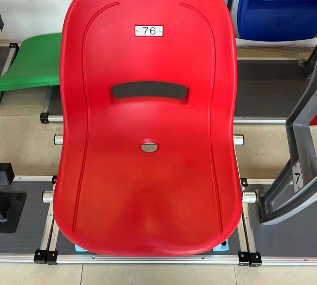 Outdoor arena seating installation featuring Eco-H HDPE 5502 blow molded full-backrest stadium seats across a tiered spectator section, showing color distribution, row spacing, and structural installation context