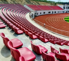 Outdoor arena seating installation featuring Eco-M HDPE 5502 blow molded stadium seats across a tiered spectator section, showing color layout, row spacing, and full structural installation context