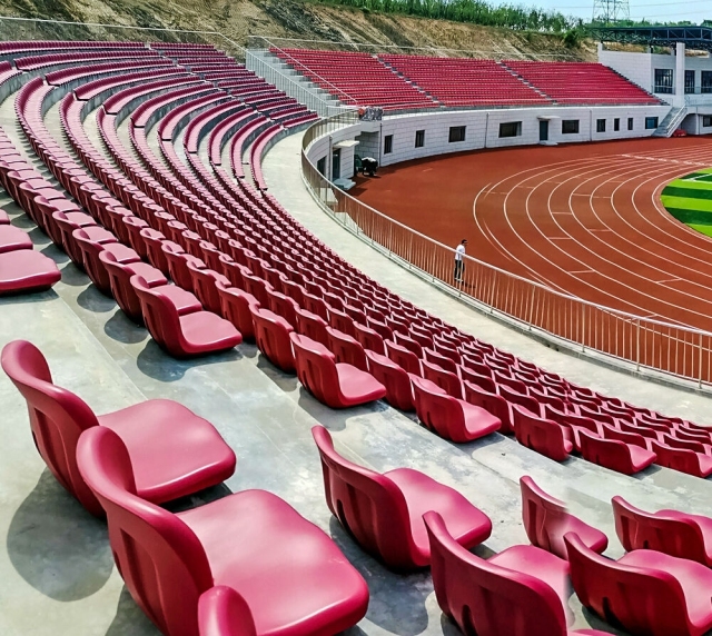 Outdoor arena seating installation featuring Eco-M HDPE 5502 blow molded stadium seats across a tiered spectator section, showing color layout, row spacing, and full structural installation context