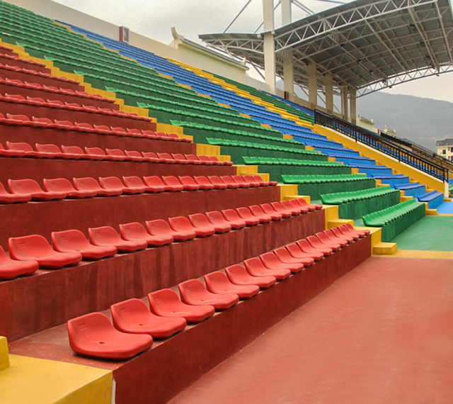 HDPE blow molded stadium seats in wall installation configuration mounted to vertical riser faces on a bleacher structure, showing bracket interface and seat positioning