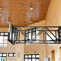 FIBA wall mounted basketball stand installed in high school gymnasium or university training hall showing side-fold backstop in deployed play position and retracted nearly-flat wall storage profile, multi-sport court floor area preserved without floor post footings, and institutional facility wall-mount integration