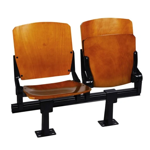 Solid wood veneered folding tip-up chair in open seated position showing natural wood veneer exterior surface with environmental protection paint finish, hot-pressure curved core anatomical profile at 440×545mm, and auditorium or theatre venue installation context